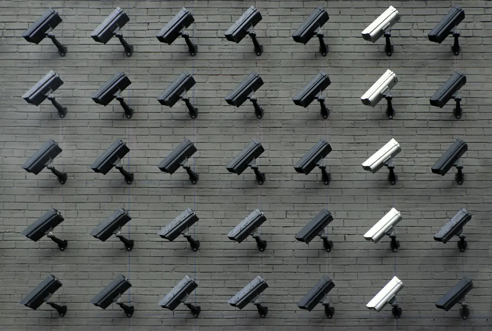 Rows of white security cameras on a dark wall
